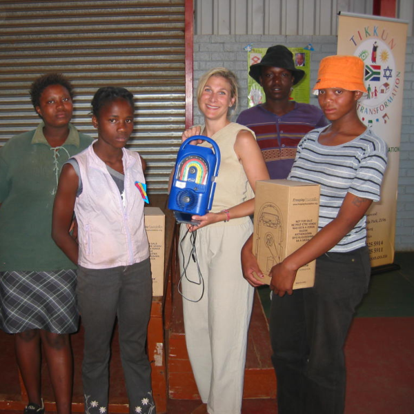 Alicia Polak holding a radio standing next to a group of people