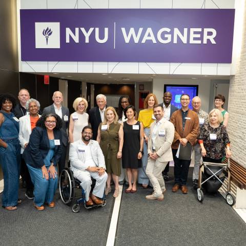 group of people posing for photo under NYU Wagner sign