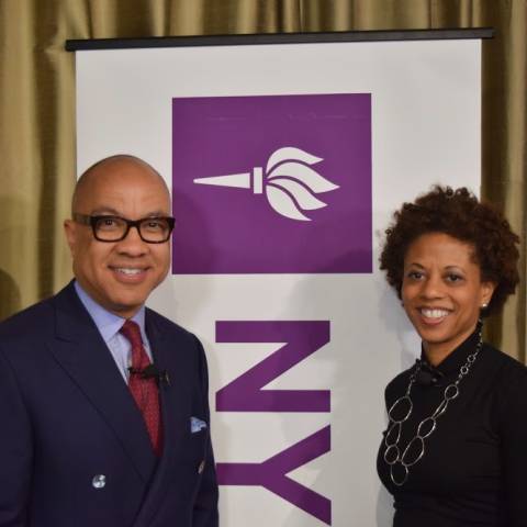 Two individuals standing in front of NYU sign 