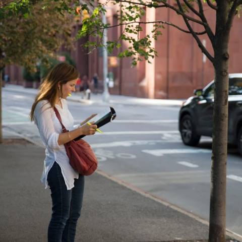 Person standing on street with notepad and pen in hand