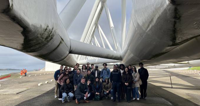 group of students smiling for camera under large metal structure