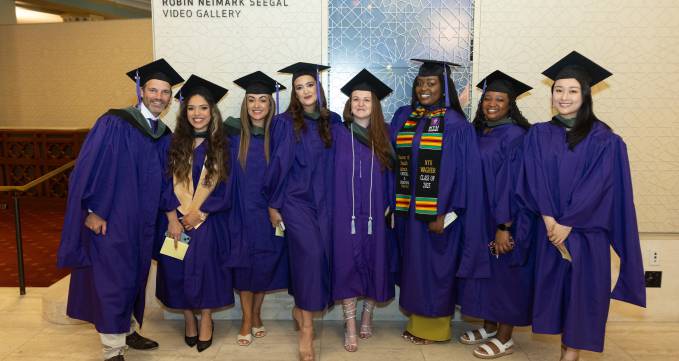 group of students in purple graduation regalia smiling for camera